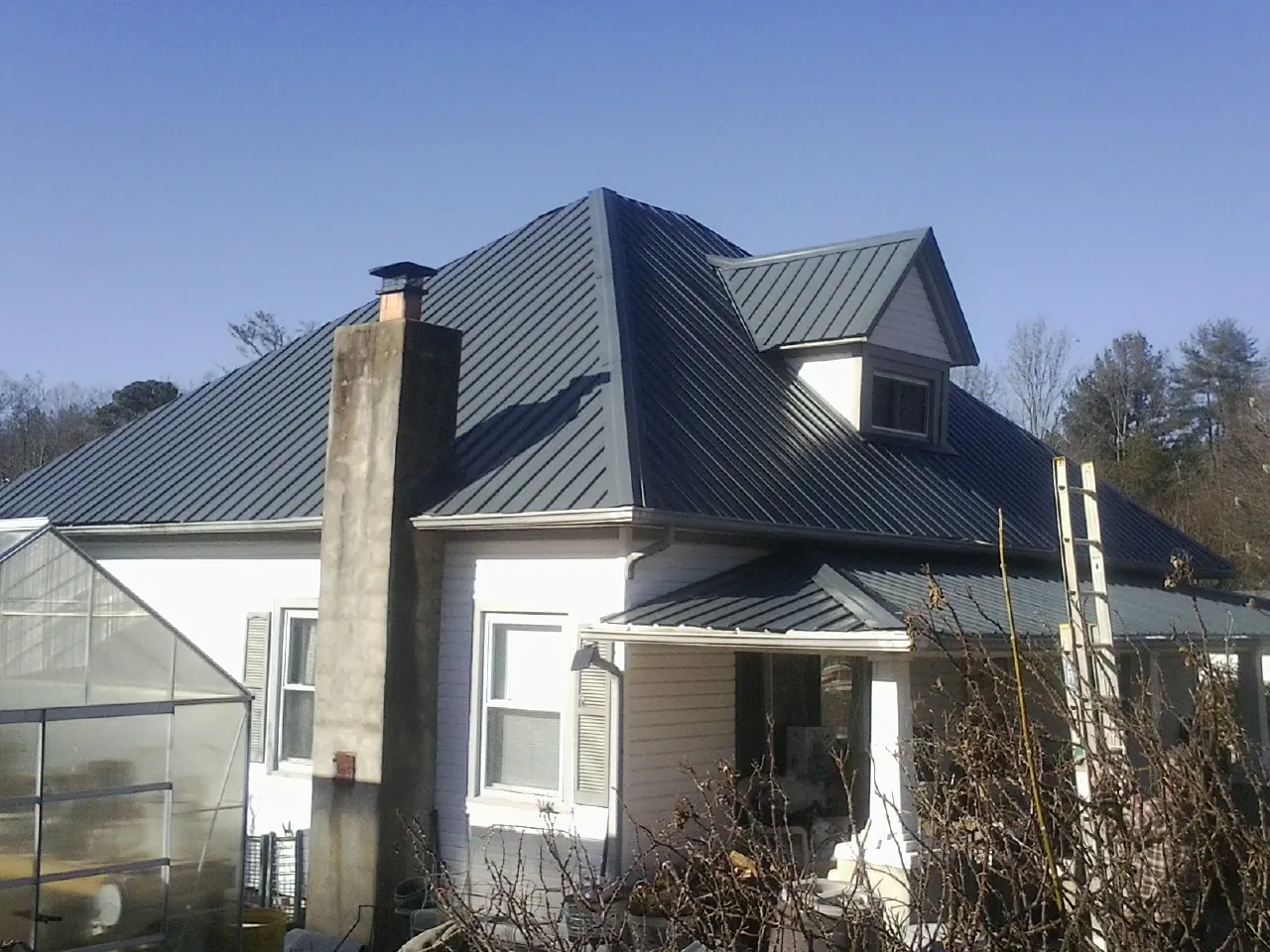 Dark blue standing seam metal roof on a white farmhouse with dormer — Slate & Tile Roof Repair by Roofing Brothers in Gas City