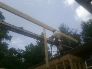 Carpenter setting a ridge beam over a new addition frame — Ice Dam Removal by Roofing Brothers in Gas City