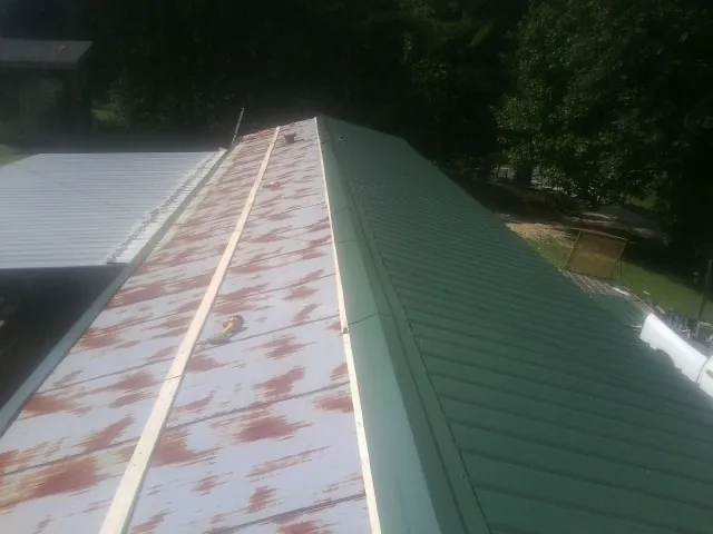 Old rusted panels beside newly installed green metal roofing — Wind Damage Roof Repair by Roofing Brothers in Gas City