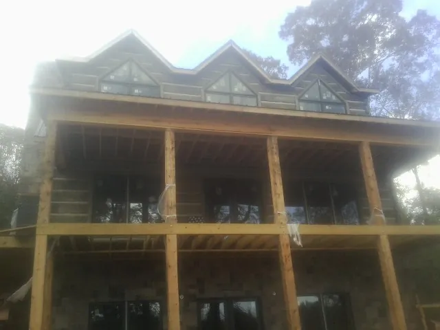 Dormers and porch framing on a large log home under construction — Roof Coating work by our crew in Gas City