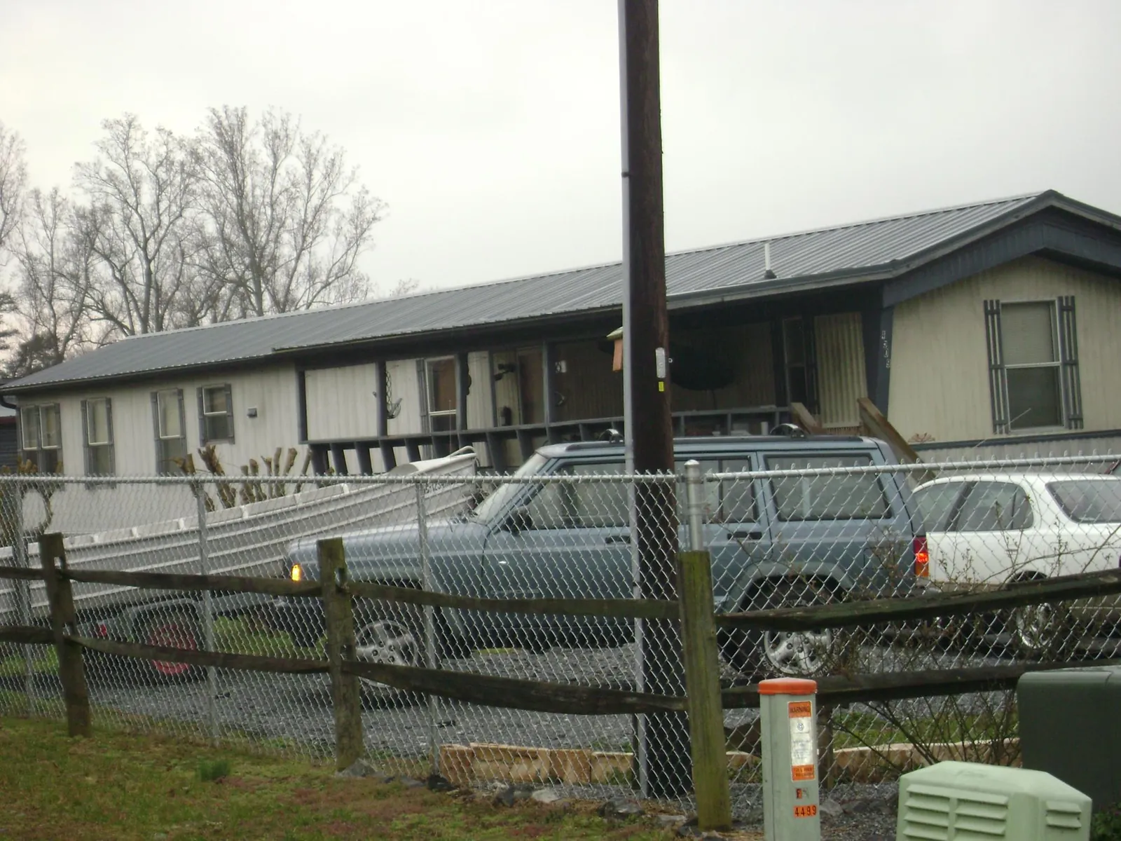 Dark metal roof on a long single story building behind a chain link fence in Gas City