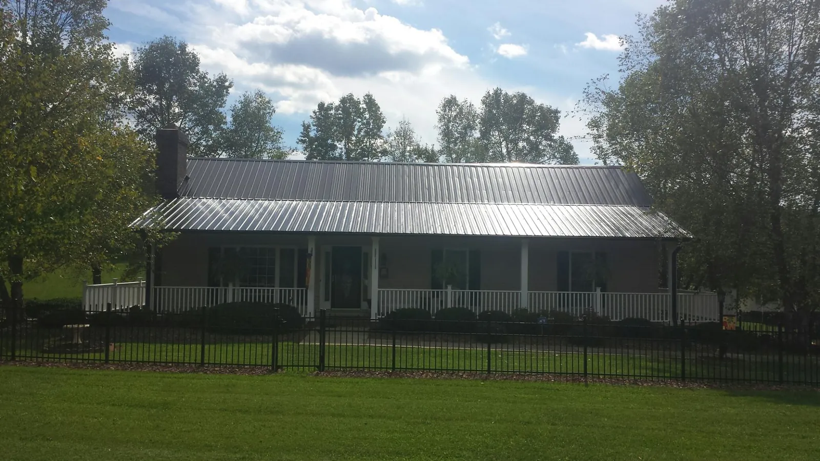 Gray metal roof on a brick ranch with a full width front porch — Gutter Guard Installation work by our crew in Gas City