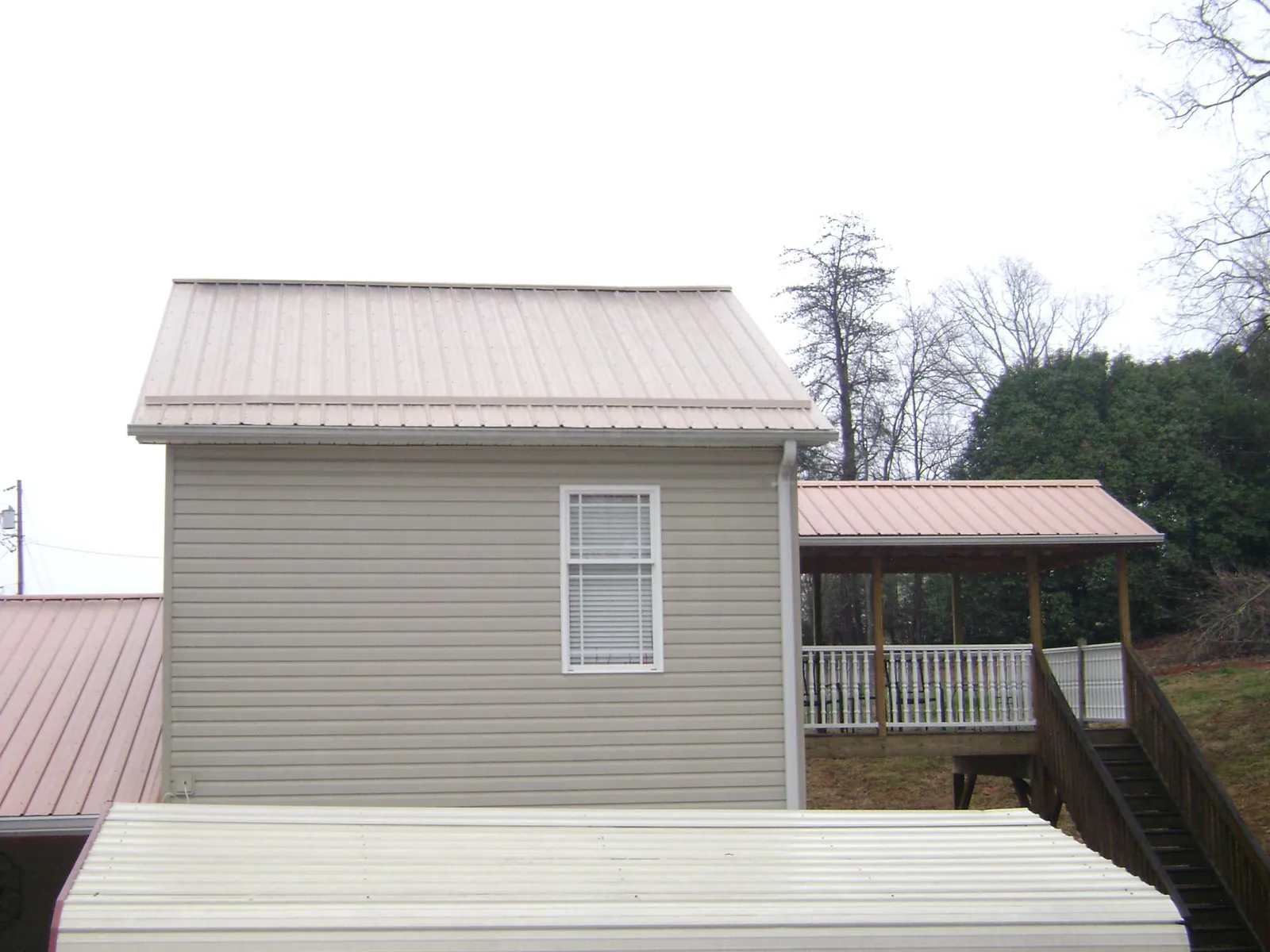 Tan metal roofs on a two story addition and attached porch, from a Roof Replacement job in Gas City