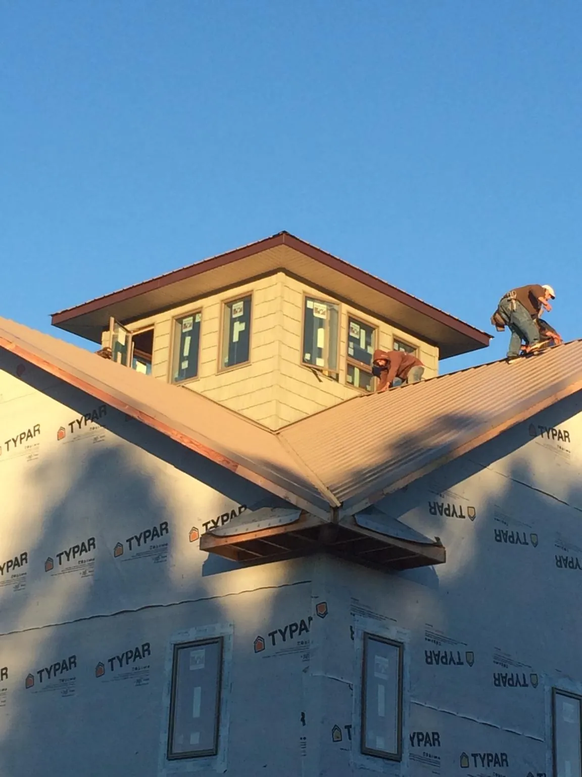 Roofers working around a rooftop cupola on a new metal roof at sunset — Roof Waterproofing in Gas City by Roofing Brothers